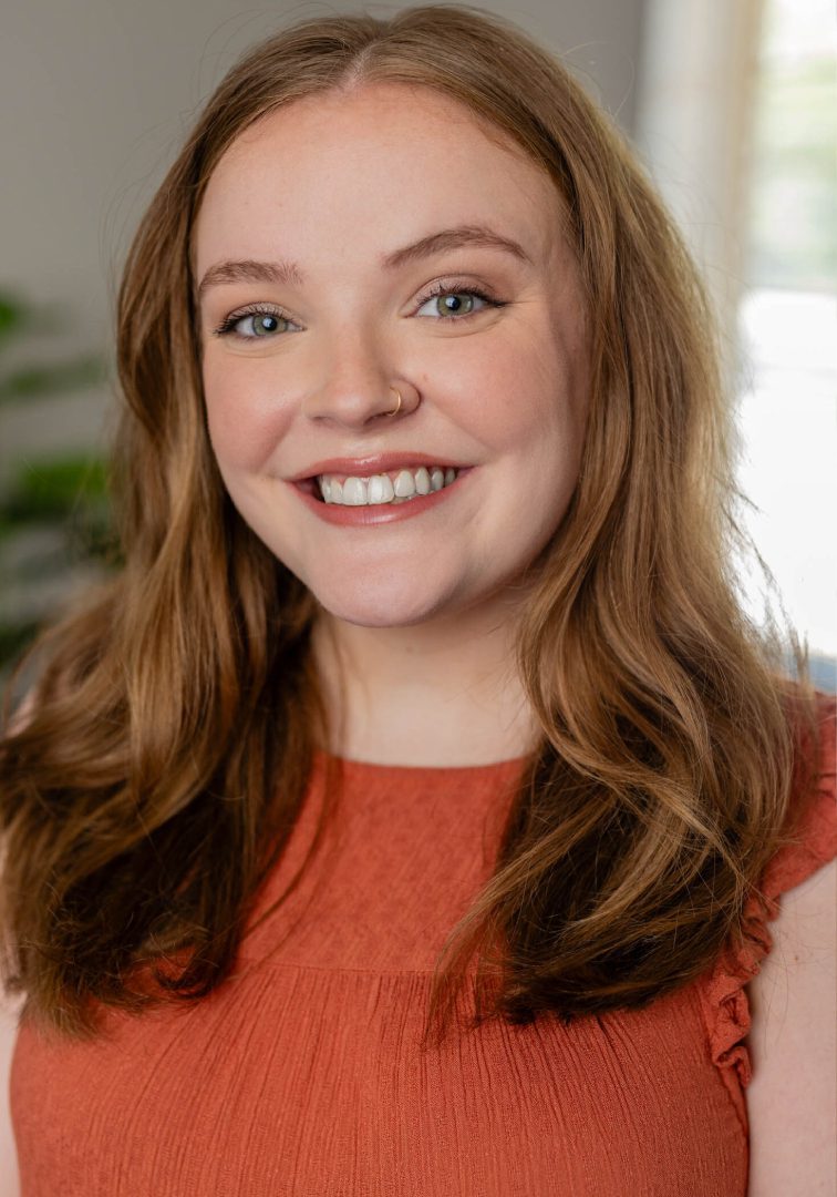 Smiling woman in an orange top.