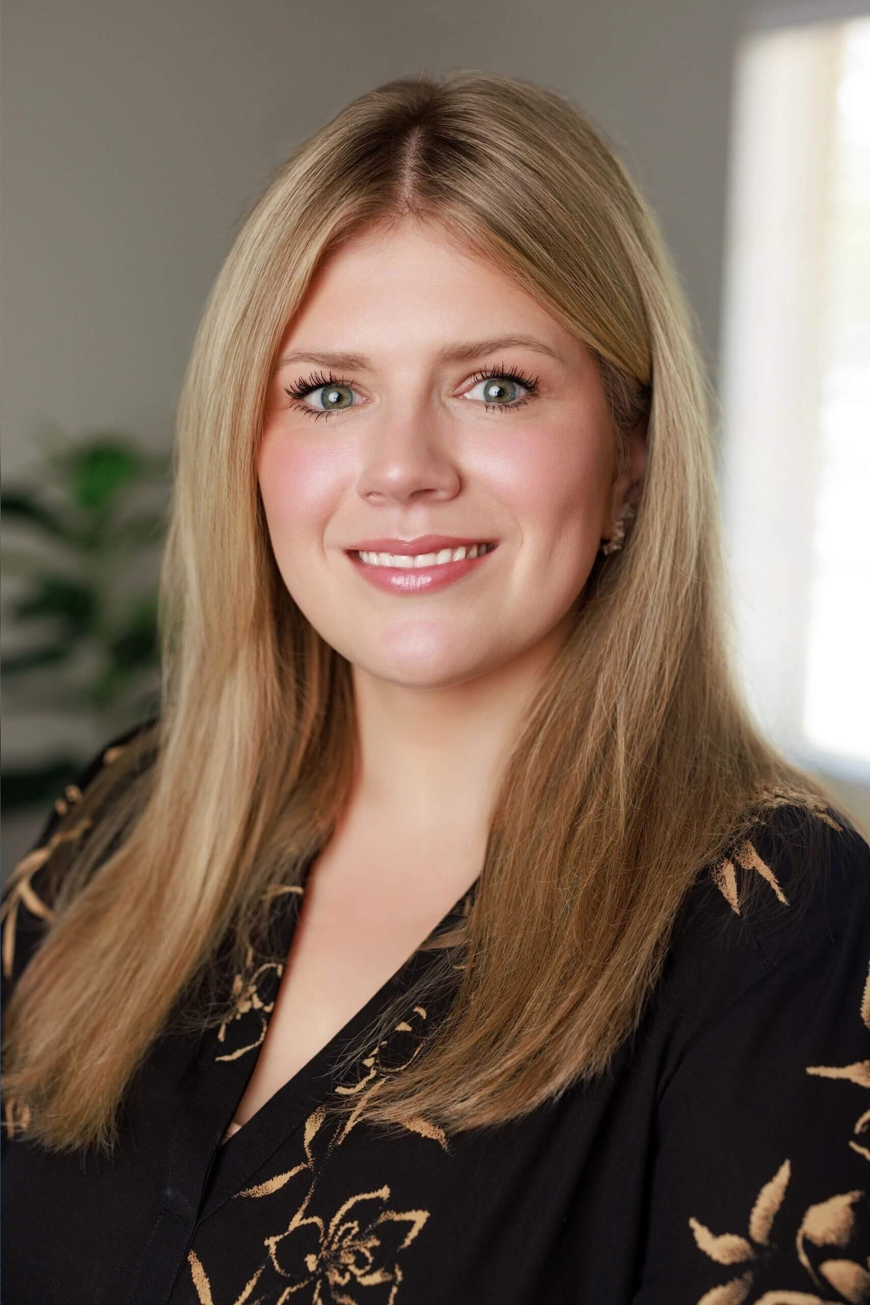 Smiling woman with long blonde hair indoors.